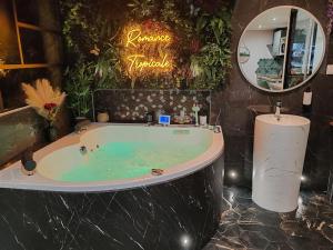 un bagno con grande vasca e specchio di Le Quai Amiénois - Romance Tropicale - SPA Romantique ad Amiens Altre 25 foto