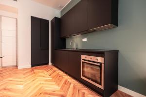 een keuken met zwarte kasten en een fornuis bij Roma Luxe Suite in Turijn