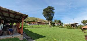 una casa con una collina verde sullo sfondo di Eco Avocado Lodge a San José de Minas
