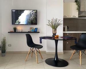 a kitchen with a table with chairs and a tv on the wall at Hygge Apartment in Durrës