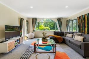 a living room with a couch and a tv at Nature Serenity Getaway with pool - deck - gardens in Auckland
