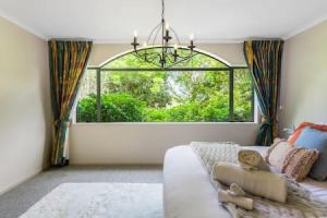 un soggiorno con divano e una grande finestra di Nature Serenity Getaway with pool - deck - gardens ad Auckland