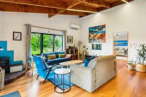 a living room with a couch and blue chairs at Serene Shoreline with seaview and spa pool in Auckland