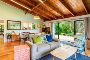 a living room with a couch and a table at Serene Shoreline with seaview and spa pool in Auckland