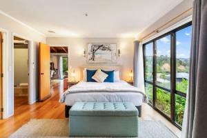 a bedroom with a bed and a large window at Serene Shoreline with seaview and spa pool in Auckland