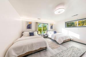 two beds in a room with white walls and windows at Starry Night Cabin at Sky Ranch in Oakhurst