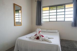 a bedroom with a bed with white sheets and a mirror at Pousada Mota in Bonito