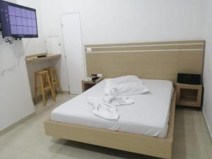 MOTEL CUPIDO (PALMIRA) في بالميرا: غرفة نوم بسرير ذو شراشف بيضاء وتلفزيون