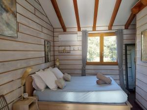 Ce lit se trouve dans une chambre en bois dotée d'une fenêtre. dans l'établissement o fil de l'eau, à Omessa