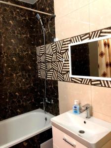 ein Badezimmer mit Waschbecken, Spiegel und Badewanne in der Unterkunft Апартаменты ПРЕМЬЕР in Kamjanez-Podilskyj
