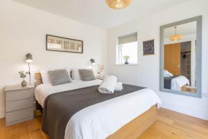 1 dormitorio con 1 cama grande y espejo en Corinium Lodge HM20 HOT TUB Lakeside Spa Property, en Somerford Keynes