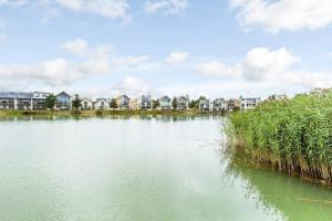 a large body of water with houses in the background at Skylark Lodge HM24 HOT TUB Lakeside Spa in Somerford Keynes