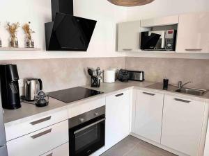 a kitchen with white cabinets and a sink and a microwave at Un havre de paix entre mer et montagne à Sant'Ambroggio in Lumio +24 photos