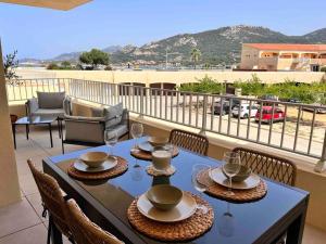 a table with chairs and glasses on a balcony at Un havre de paix entre mer et montagne à Sant'Ambroggio in Lumio