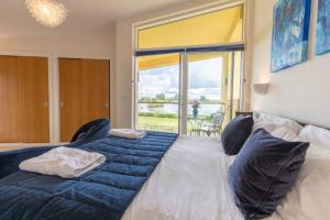 een slaapkamer met een groot bed en een groot raam bij Tawny House CW6 Lakeside Spa Property in Somerford Keynes
