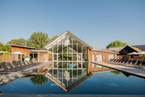 a greenhouse with chairs and a pool of water at Tawny House CW6 Lakeside Spa Property in Somerford Keynes