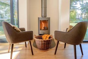 two chairs and a basket in front of a fireplace at Natures Retreat HM99 HOT TUB Lakeside Spa in Somerford Keynes +56 photos