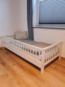 a white crib in a room with a window at Top modernes Appartement mit Blick ins Grüne in Kißlegg