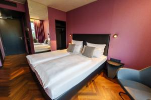 ein großes Bett in einem Zimmer mit einer lila Wand in der Unterkunft Roomreich in Ingolstadt