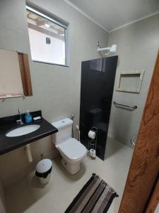 a bathroom with a toilet and a sink and a shower at Vila Guaiamum in Cumuruxatiba