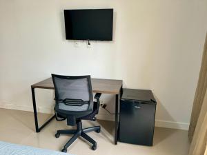 a desk with a chair and a television on a wall at Suite privativa na Barra da Tijuca, RJ - Neolink Stay in Rio de Janeiro