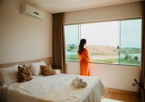 a woman looking out the window of a hotel room at Hotel Chalé Capitólio in Capitólio