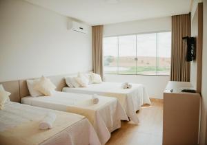 a hotel room with two beds and a window at Hotel Chalé Capitólio in Capitólio