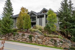 a large house with a stone retaining wall at Renovated Lynx Property - Spacious 4 bedroom with private balcony and hot tub! in Whistler