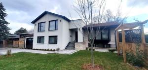 a white house with a tree in the yard at Private apartment with garden, 25 min to Downtown in Toronto