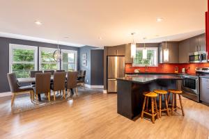 an open kitchen and dining room with a table and chairs at Renovated Lynx Property - Spacious 4 bedroom with private balcony and hot tub! in Whistler