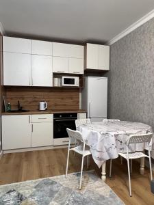 アスタナにある2х комнатная квартира Астана Левый берегのキッチン(テーブル、白いキャビネット付)