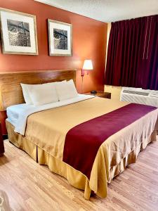 un grande letto in una camera d'albergo con parete rossa di Executive Inn Schenectady Downtown a Schenectady