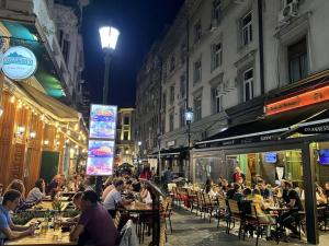 a group of people sitting at tables in a street at night at Old City Apartment in Bucharest