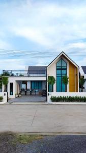 a large white house with palm trees in front of it at F&F pool villa Rayong in Rayong