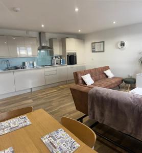 een woonkamer met een bank en een keuken bij Rooftops Apartment in Bletchley