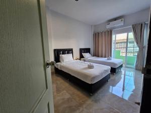 - une chambre avec 2 lits et une porte ouverte dans l'établissement Ban Chahomm Guesthouse, à Betong