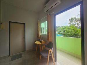 une chambre avec une chaise, une table et une fenêtre dans l'établissement Ban Chahomm Guesthouse, à Betong
