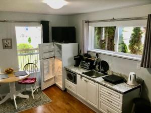 uma cozinha com um frigorífico, um lavatório e uma mesa em Telco House B&B em Port Hardy