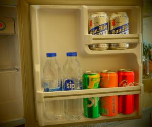 a refrigerator filled with drinks and cans of soda at Stanford Suites, South Forbes - Standard Room with pool in Silang