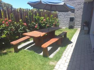 una mesa de madera y un banco con sombrilla en Flats da Ilha 2 Quartos en Marechal Deodoro