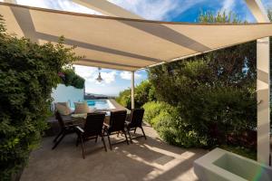 a patio with a table and chairs under an umbrella at 270 Oias View in Oia