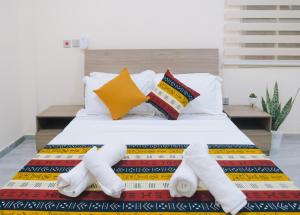 a bed with white sheets and pillows on it at Cozy Apartments East Legon in Accra