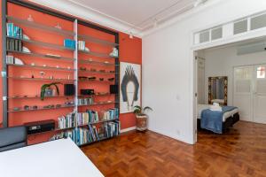 Charme na Urca - Vista arborizada - JLA301 Z5 في ريو دي جانيرو: غرفة معيشة مع جدران برتقالية ورف كتاب