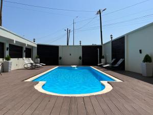 a swimming pool on a patio with a wooden deck at Villa Magnum in Douala