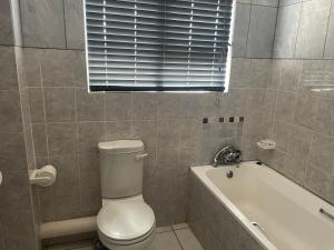 a bathroom with a toilet and a bath tub at 3The Olive Complex Richards Bay 3900 in Richards Bay