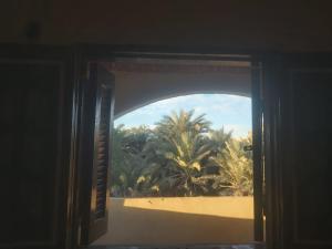 an open door with a view of a beach and palm trees at Oum House in Siwa