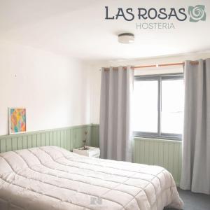 ein Schlafzimmer mit einem großen Bett und einem Fenster in der Unterkunft Hostería Las Rosas in Esquel