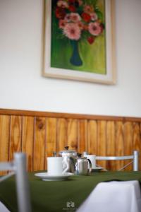 uma mesa com panelas de chá e um vaso de flores em Hostería Las Rosas em Esquel