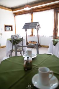 una mesa con mantel verde y una taza de café en Hostería Las Rosas en Esquel