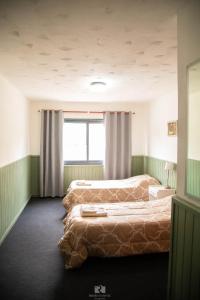 2 Betten in einem Zimmer mit Fenster in der Unterkunft Hostería Las Rosas in Esquel